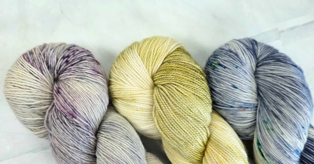 Image showing 3 different skeins of 4ply weight yarn. One is a single ply, one is 2ply and the 3rd is 4ply.