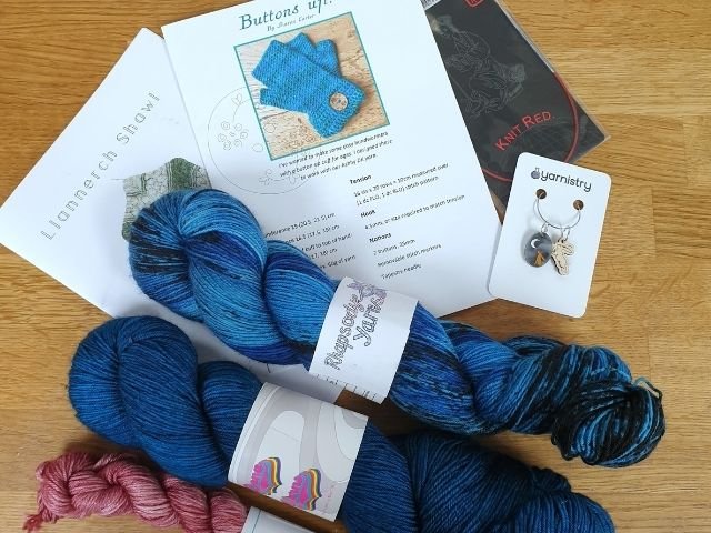 Haul from a show - a selection of patterns, skeins of yarn, stitch markers and needles
